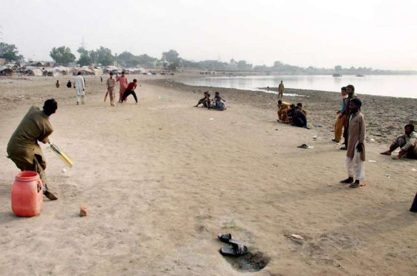 لاہور: دریائے راوے کے کنارے خانہ بدوش لڑکے کرکٹ کھیلنے میں ..
