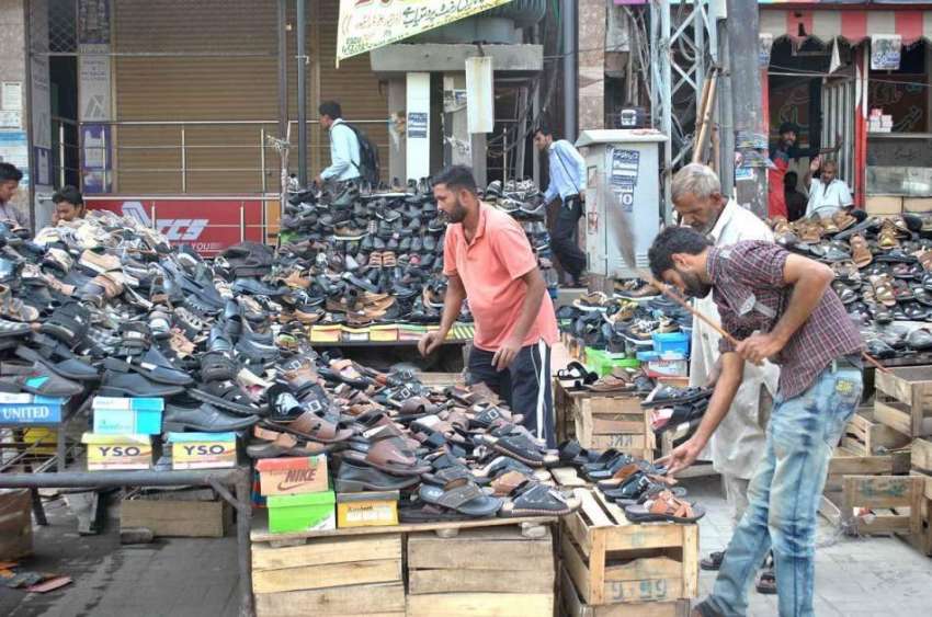 لاہور: دوکاندار سڑک کنارے جوتوں کا سٹال لگائے گاہکوں کے ..