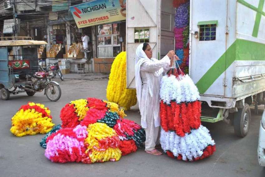 لاہور: محنت کش خاتون مصنوعی پھول فروخت کے لیے سجا رہی ہے۔