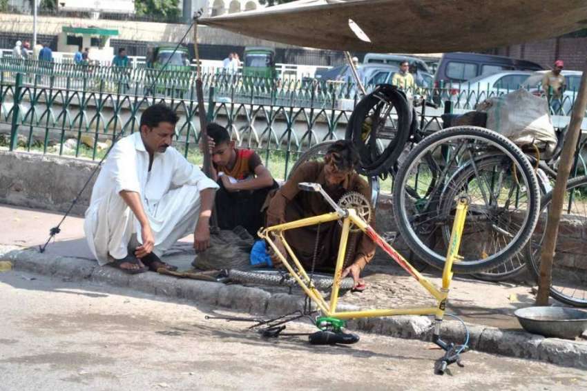 لاہور: محنت کش سڑک کنارے لگائی ورکشاپ میں سائیکل مرمت کر ..