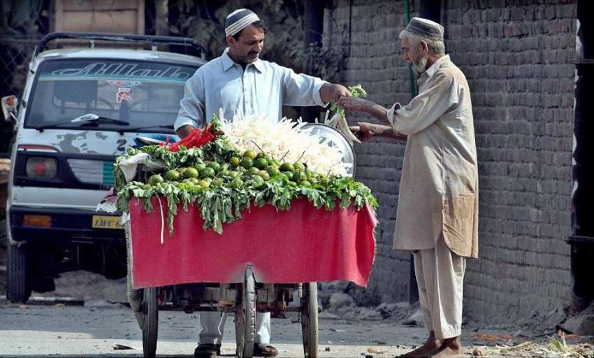 راولپنڈی: ایک شخص ریڑھی بان چاٹ مصالحہ لگی مولیاں خرید رہا ..