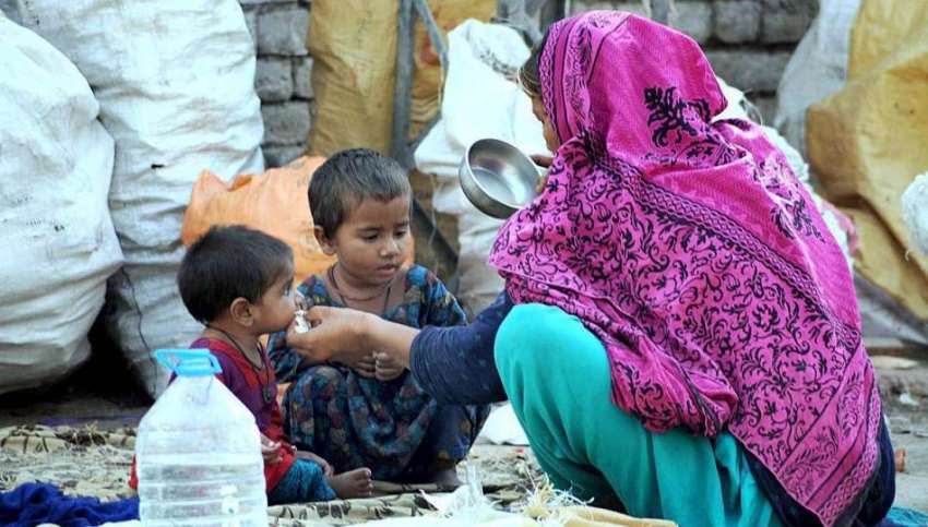 راولپنڈی: خانہ بدوش خاتون فٹ پاتھ پر بیٹھی اپنے بچوں کا کھانا ..