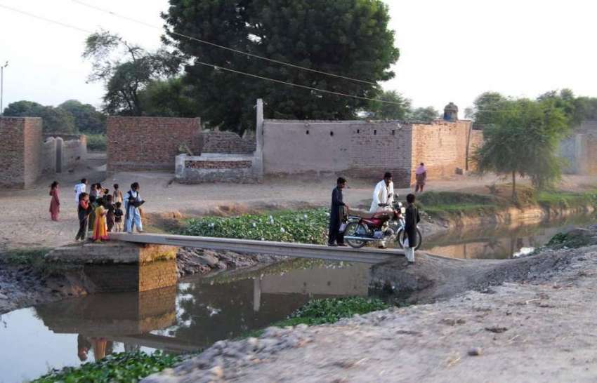 ملتان: نہر کے اوپر بنائے گئے عارضی پل سے موٹر سائیکل سوار ..