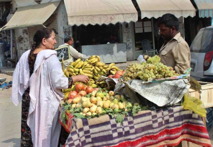 لاہور: پھل فروش سے ایک بزرگ خاتون پھل خرید رہی ہے۔