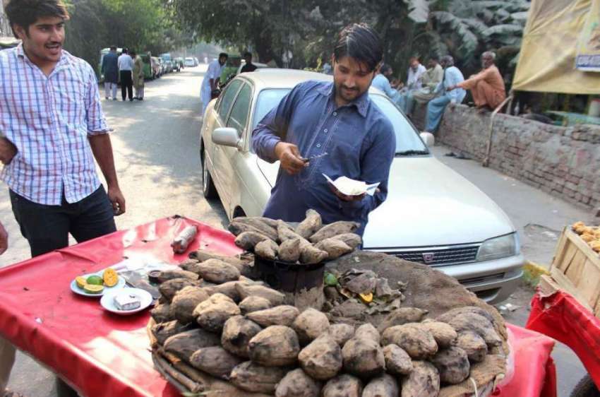 لاہور : شہری ایک ریڑھی بان سے کوئلوں پر تیار کی گئی شکر قندی ..