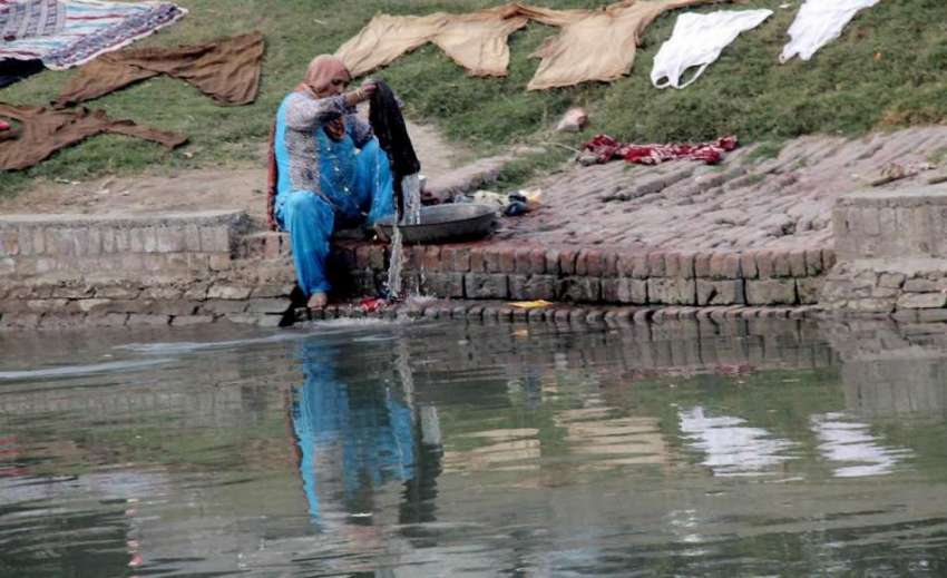 لاہور: ایک خاتون نہر کنارے بیٹھی کپڑے دھونے میں مصروف ہے۔