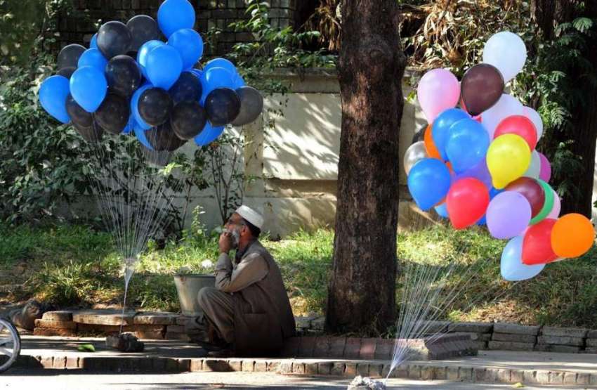 اسلام آباد: محنت کش سڑک کنارے غبارے فروخت کے لیے گاہکوں کے ..