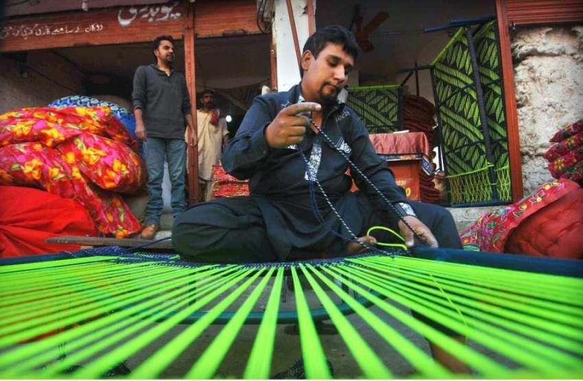 اسلام آباد: محنت کش اپنی دکان پر چارپائی بنا رہا ہے۔