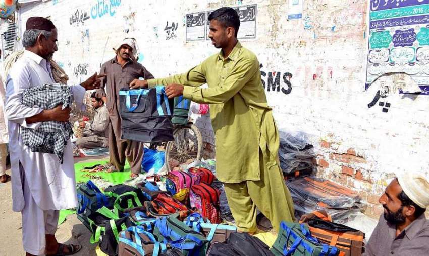ملتان: مزدور سڑک کنارے مختلف اقسام کے بیگ فروخت کر رہا ہے۔
