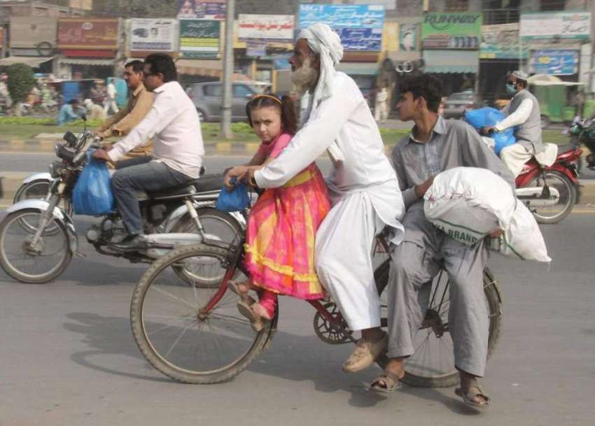 لاہور: ایک بزرگ شہری اپنے بچوں کو سائیکل پر بیٹھا کر لیجا ..