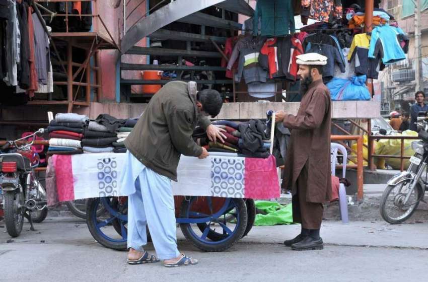اسلام آباد: ایک شہری ریڑھی بان سے پرانے گرم کپڑے پسند کر ..