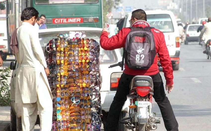 راولپنڈی: موٹر سائیکل سوار شہری سڑک کنارے لگے سٹال سے عینک ..