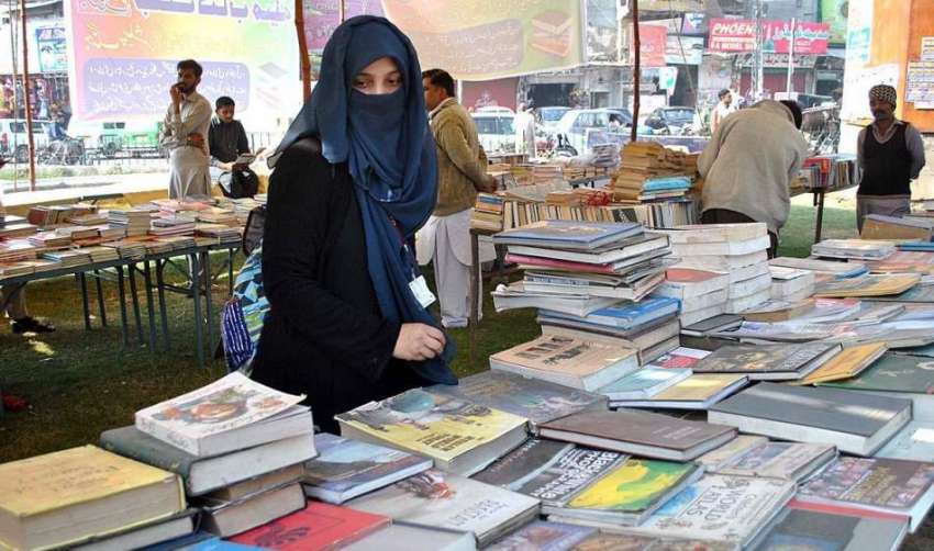 لاہور: سڑک کنارے لگے پرانے کتابوں کے سٹال سے ایک طالبہ کتابیں ..