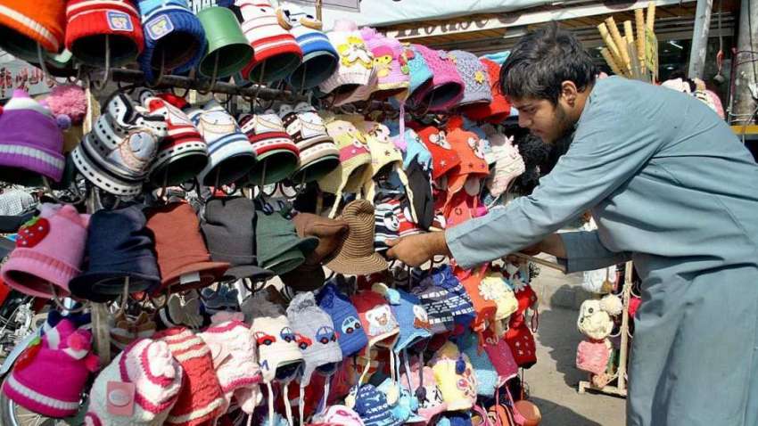 لاہور: دکاندار فروخت کے لیے گرم ٹوپیاں سجا رہا ہے۔