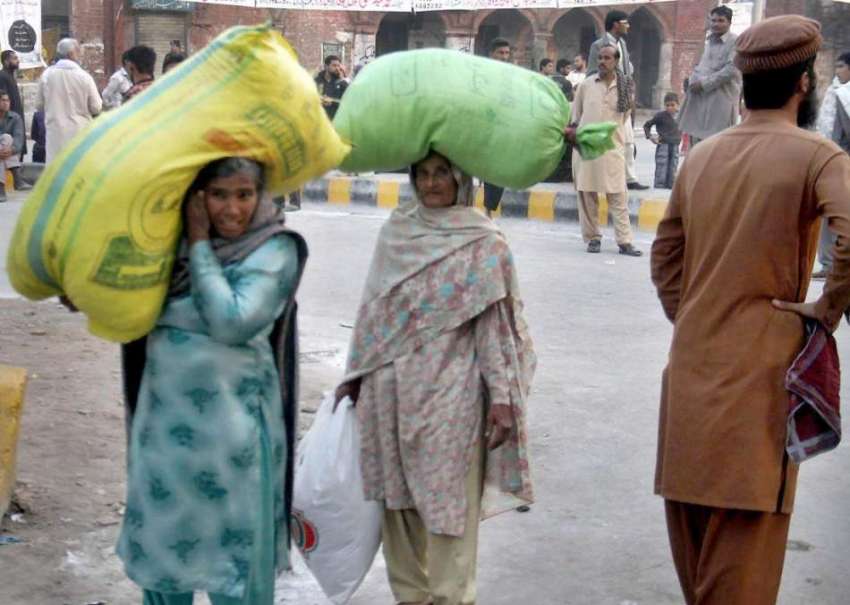 لاہور: دو خواتین سر پر بھاری سامان کے بورے رکھے جا رہی ہیں۔