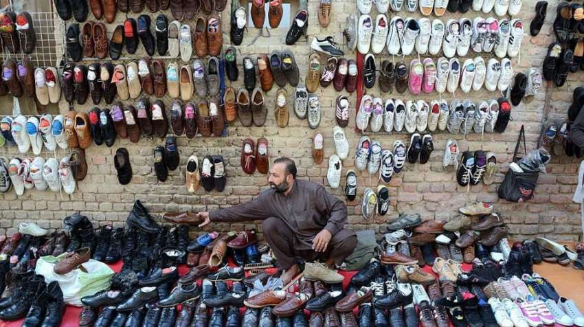 لاڑکانہ: دوکاندار پرانے جوتے فروخت کے لیے سجا رہا ہے۔