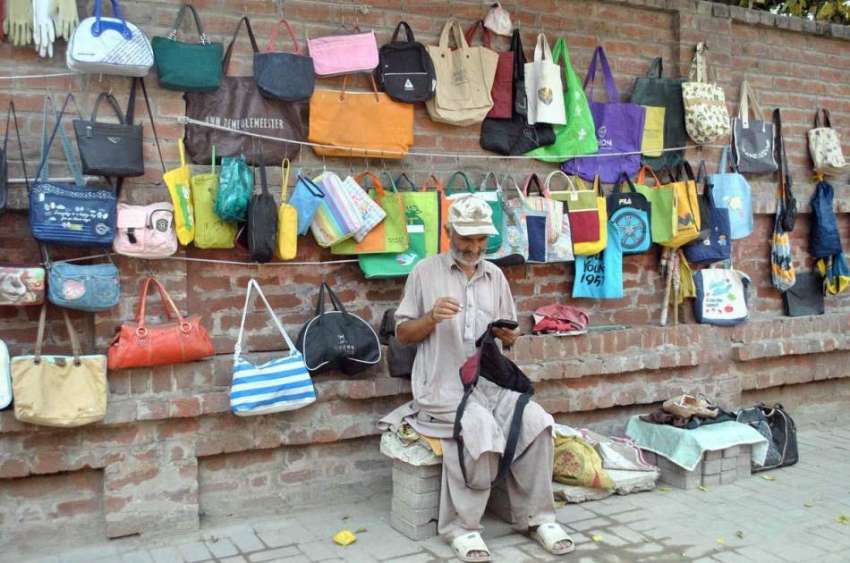 لاہور: محنت کش سڑک کنارے بیگ فروخت کے لیے سجائے گاہکوں کے ..