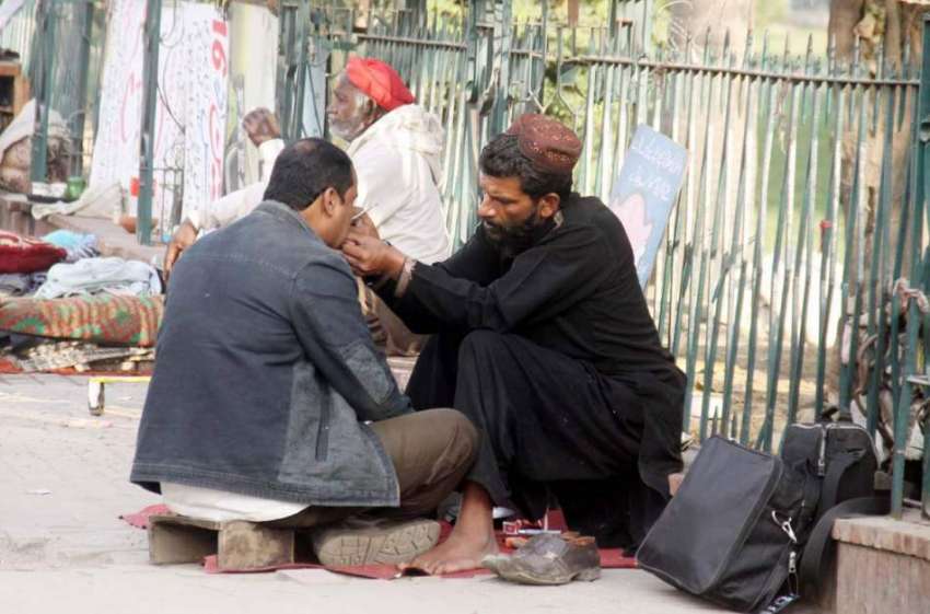 لاہور: ایک شہری سڑک کنارے بیٹھے عطائی سے اپنے دانتوں کا علاج ..