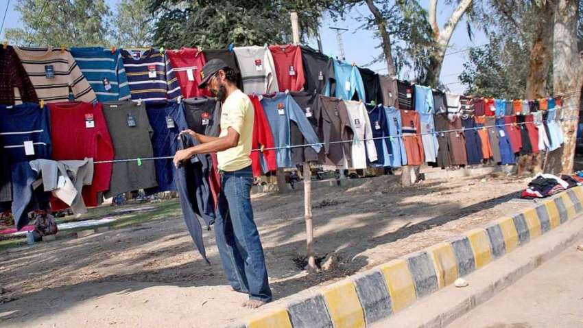 حیدر آباد: محنت کش سڑک کنارے فروخت کے لیے کپڑے تاروں پر لٹکا ..