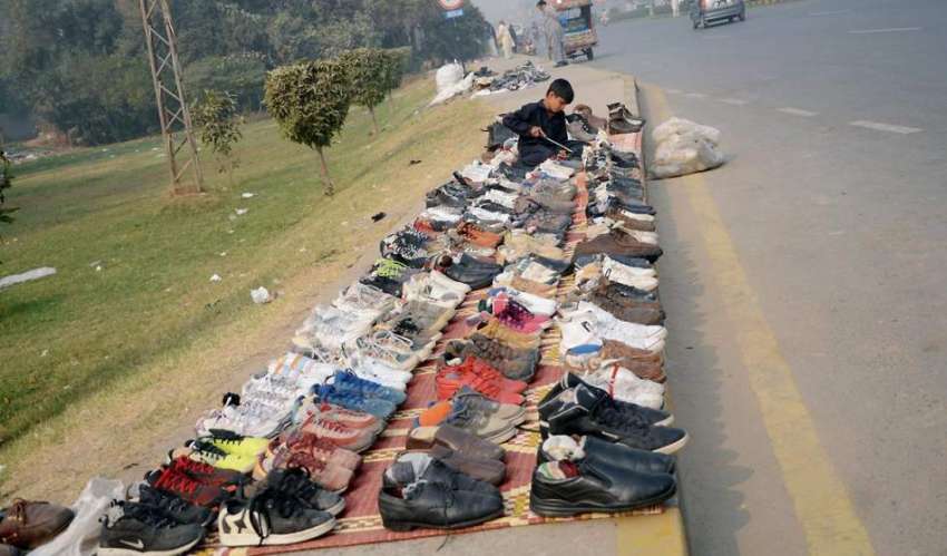 فیصل آباد: فٹ پاتھ پر پرانے جوتوں کا سٹال لگائے کمسن بچہ ..