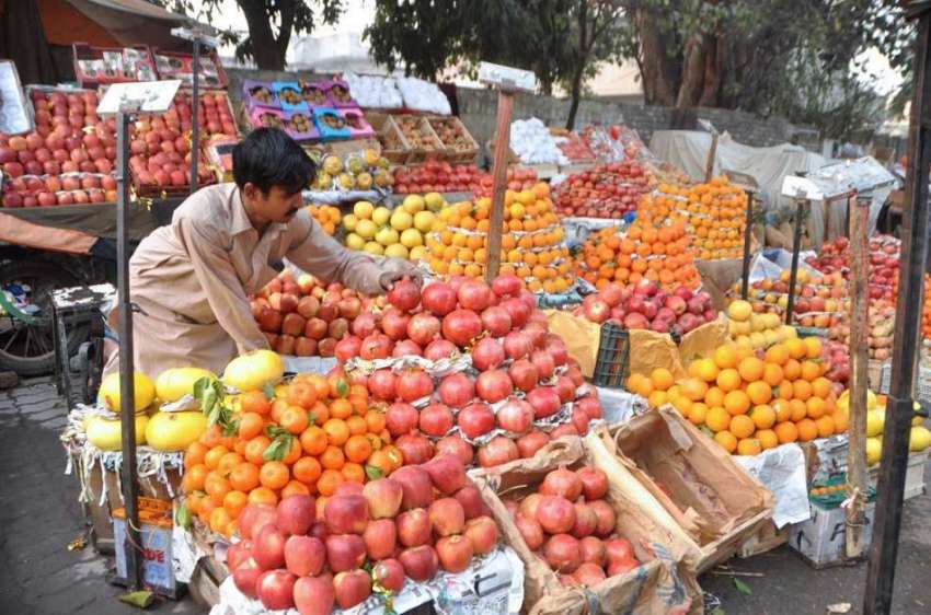 لاہور: ریڑھی بان فروخت کے لیے ریڑھی پر فروٹ سجا رہا ہے۔
