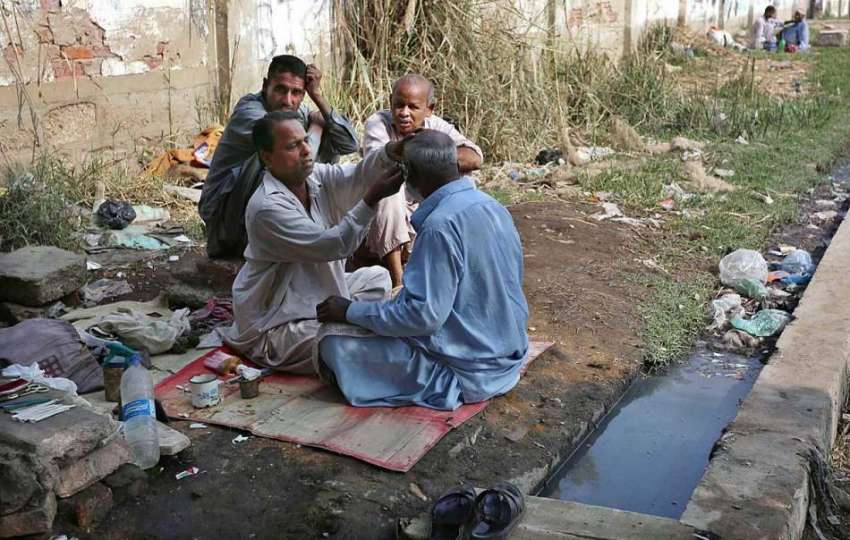 حیدر آباد: رواتی حجام زمین پر بیٹھا ایک شہری کی شیو بنا رہا ..