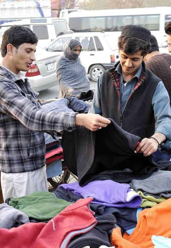 راولپنڈی: ایک نوجوان ریڑھی بان سے گرم کپڑے پسند کر رہا ہے۔