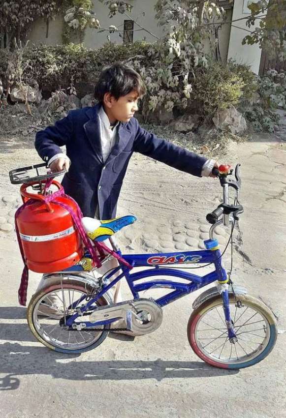 راولپنڈی: ایک بچہ اپنے سائیکل پر سلنڈر رکھے گیس بھروانے ..