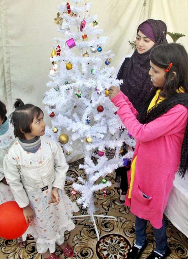 لاہور: ایک بچی کرسمس کی تیاریوں کے سلسلے میں کرسمس ٹری سجا ..