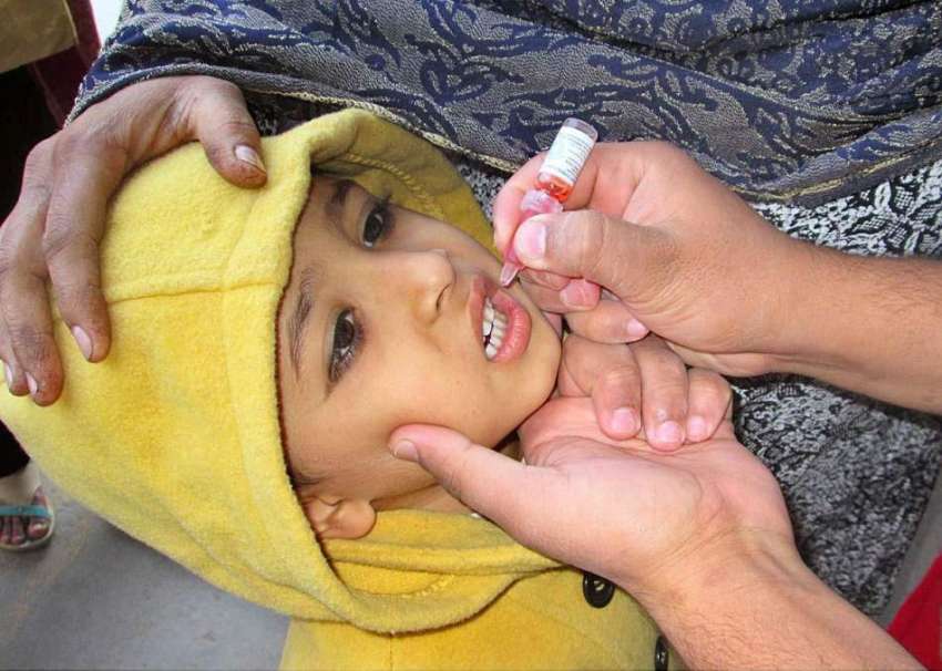 فیصل آباد: لیڈی ہیلتھ ورکر ایک بچے کو پولیے کے قطرے پلا رہی ..