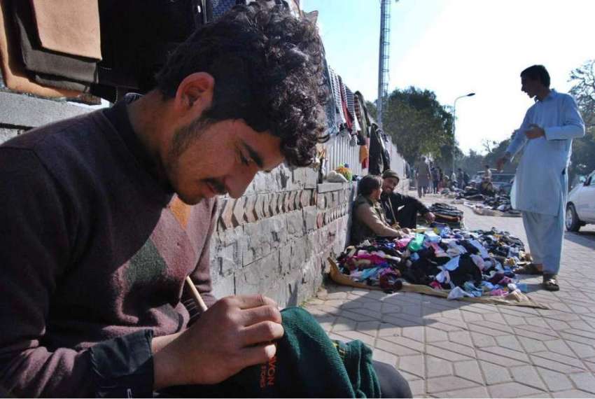 اسلام آباد: ایک محنت کش پرانے سویٹر فروخت کے لیے رفو کر رہا ..
