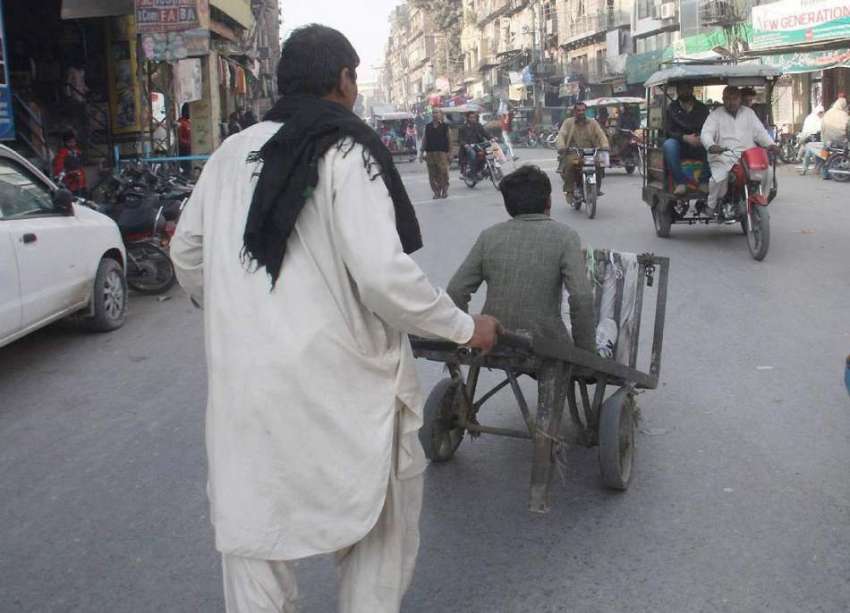 لاہور: ایک محنت کش بچے کو ہتھ ریڑھی پر بٹھائے جا رہا ہے۔