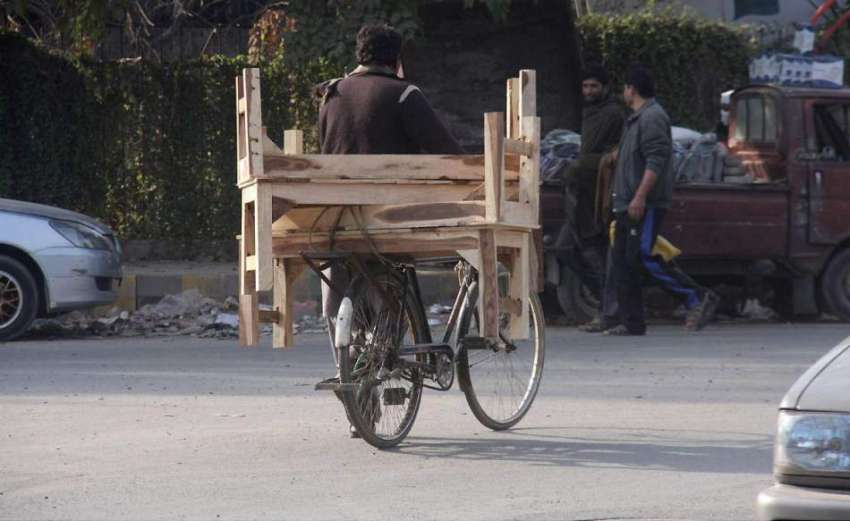 لاہور: ایک شخص سائیکل پر لکڑی کے بینچ رکھے جا رہا ہے۔