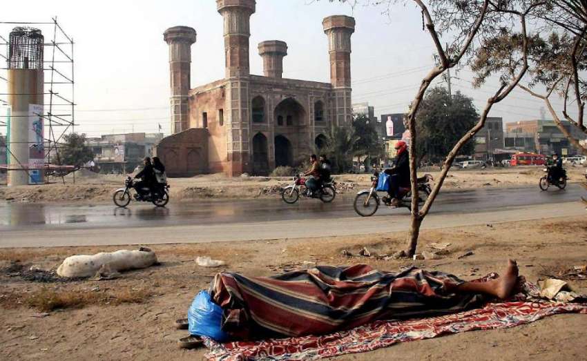 لاہور: ایک بے گھر شخص شدید سردی میں سڑک کنارے کھلے آسمان ..