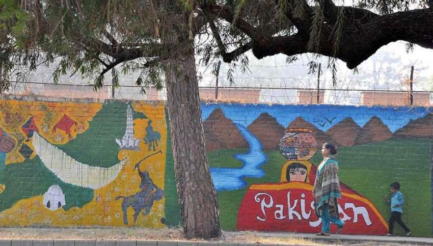اسلام آباد: ایک خاتون اپنے بچے کے ہمراہ پینٹنگ والی دیوار ..
