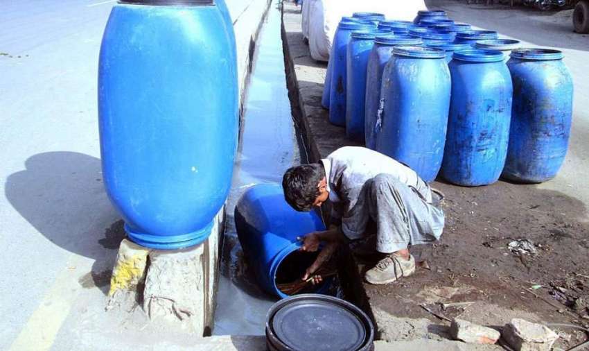 فیصل آباد: ایک مزدور کیمیکل والے ڈرم دھونے میں مصروف ہے۔