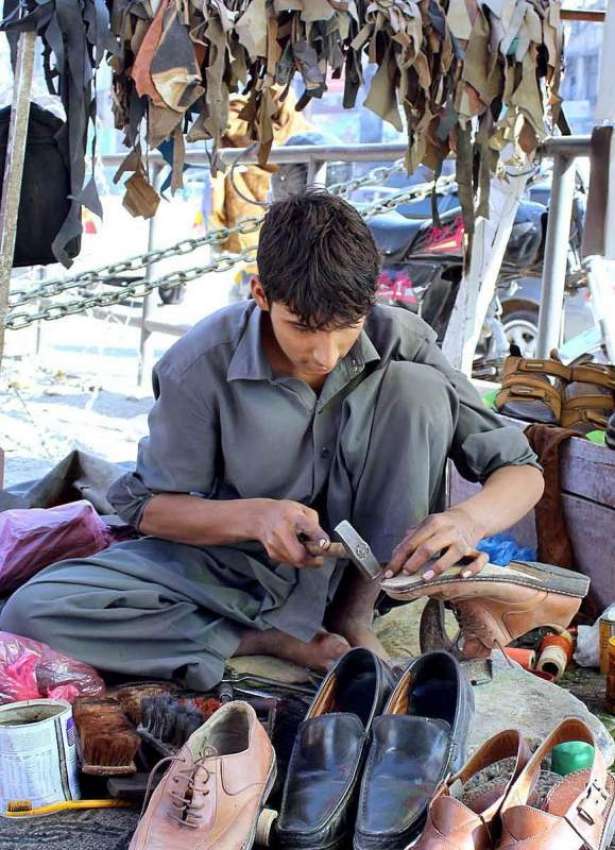 پشاور: نوجوان محنت کش سڑک کنارے بیٹھا جوتے مرمت کر رہا ہے۔