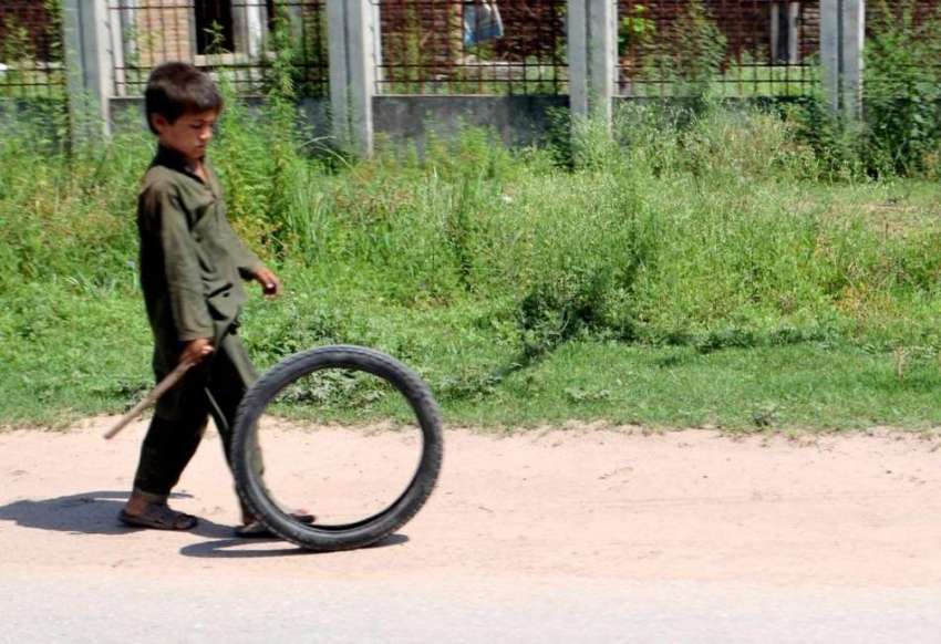راولپنڈی: ایک خانہ بدوش بچہ پرانے ٹائر سے کھیل رہا ہے۔