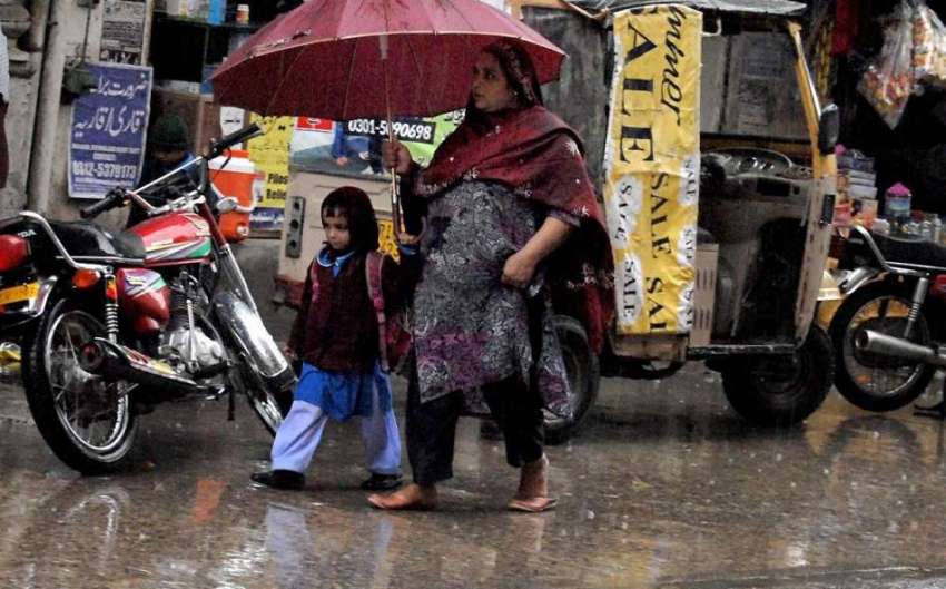 راولپنڈی: بارش کے دوران ایک خاتون چھتری تھامے بچی کو سکول ..