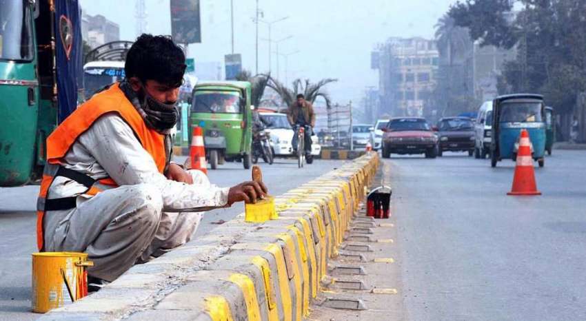 پشاور: ایک مزدور روڈ لائنز لگانے میں مصروف ہے۔