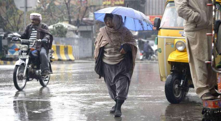 راولپنڈی: ایک معمر شخص بارش کے دوران چھتری تانے جا رہا ہے۔