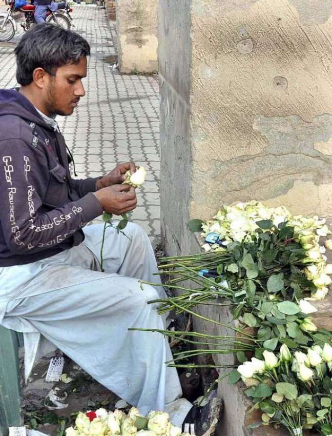 اسلام آباد: ایک محنت کش سڑک کنارے فروخت کے لیے پھولوں کا ..