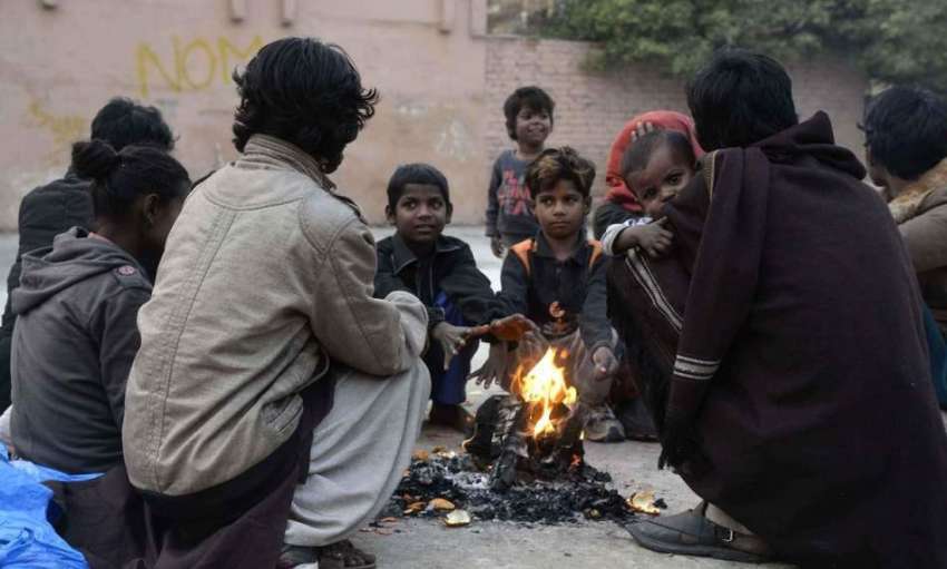 راولپنڈی: خانہ بدوش خاندان کے افراد سردی کی شدت کم کرنے کے ..