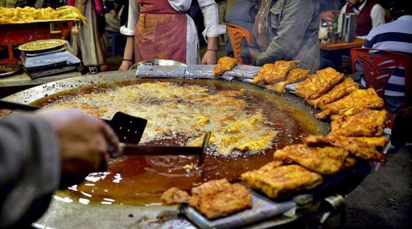 راولپنڈی: دکاندار فروخت کے لیے مچھلی فرائی کر رہا ہے۔