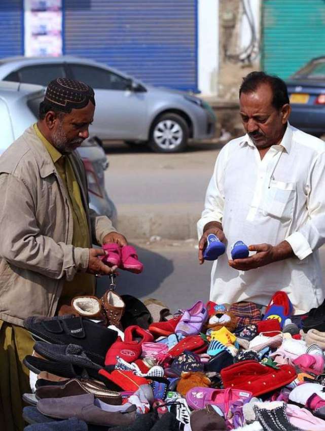 حیدر آباد: ایک شہری ریڑھی بان سے بچوں کے جوتے پسند کر رہا ..