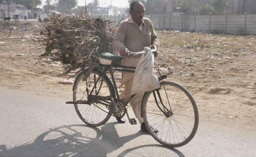 لاہور: ایک شخص گھر کا چولہا جلانے کے لیے سائیکل پر لکڑیاں ..