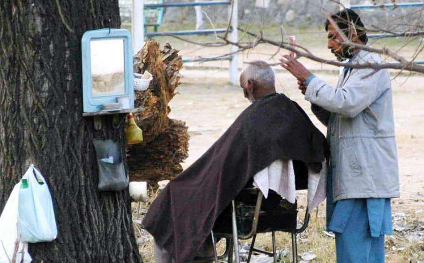 اسلام آباد: حجام سڑک کنارے ایک شہری کے بال تراش رہا ہے۔