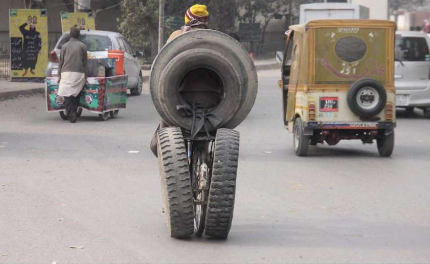 لاہور: ایک شخص سائیکل پر دیگ اور پرانے ٹائر لیکر جا رہا ہے۔