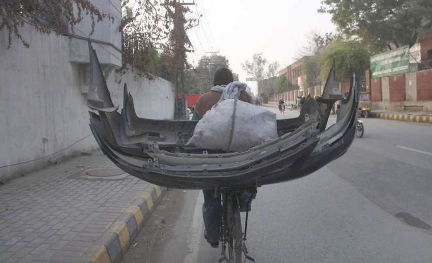 لاہور: ایک شخص سائیکل پر گاڑیوں کے پرانے بمپر رکھ کر لیجا ..