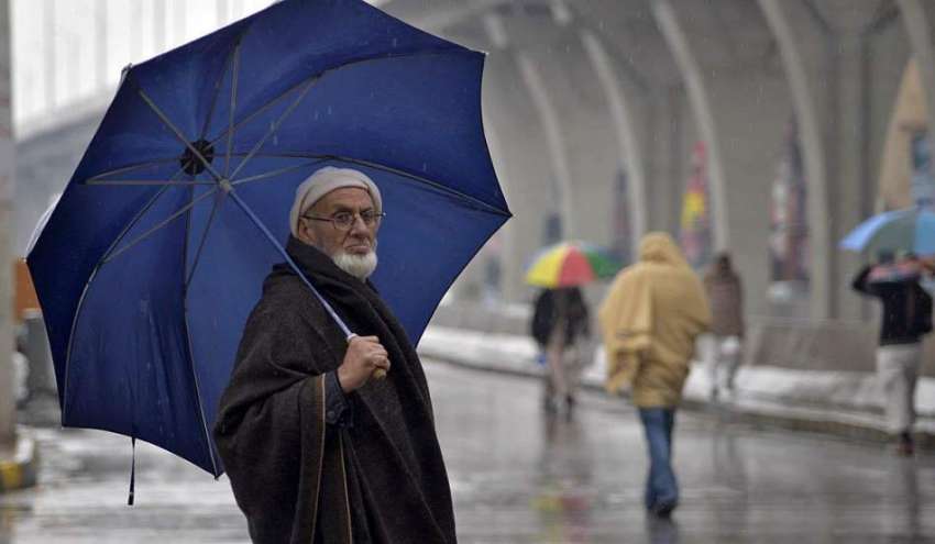 راولپنڈی: ایک بزرگ شہری بارش سے بچنے کے لیے چھتری تانے جا ..